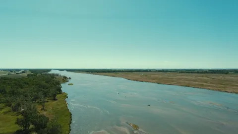 Aerial view of the Platte River flowing between forested and open floodplain areas.