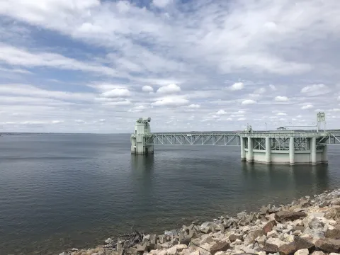 Large metal intake structure extending into Lake McConaughy with rocky shoreline in the foreground.