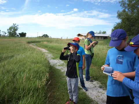 Group of students birdwatching and taking notes along a trail.